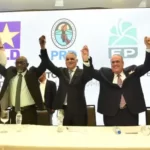 Momentos en que representantes del PRD PLD y Fuerza del Pueblo levantan las manos tras la firma del acuerdo de la alianza opositora para las elecciones de