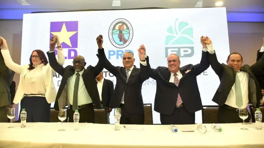 Momentos en que representantes del PRD PLD y Fuerza del Pueblo levantan las manos tras la firma del acuerdo de la alianza opositora para las elecciones de